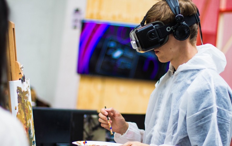 man wearing black virtual reality headset while painting near