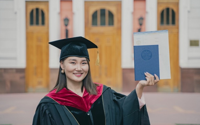 a woman in a graduation cap and gown holding a diploma